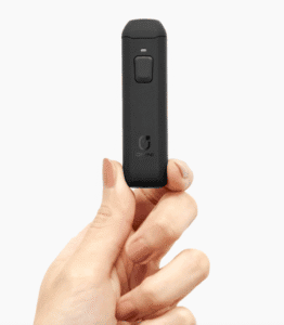 Hand holding a black vape cartridge device for cannabis oil.